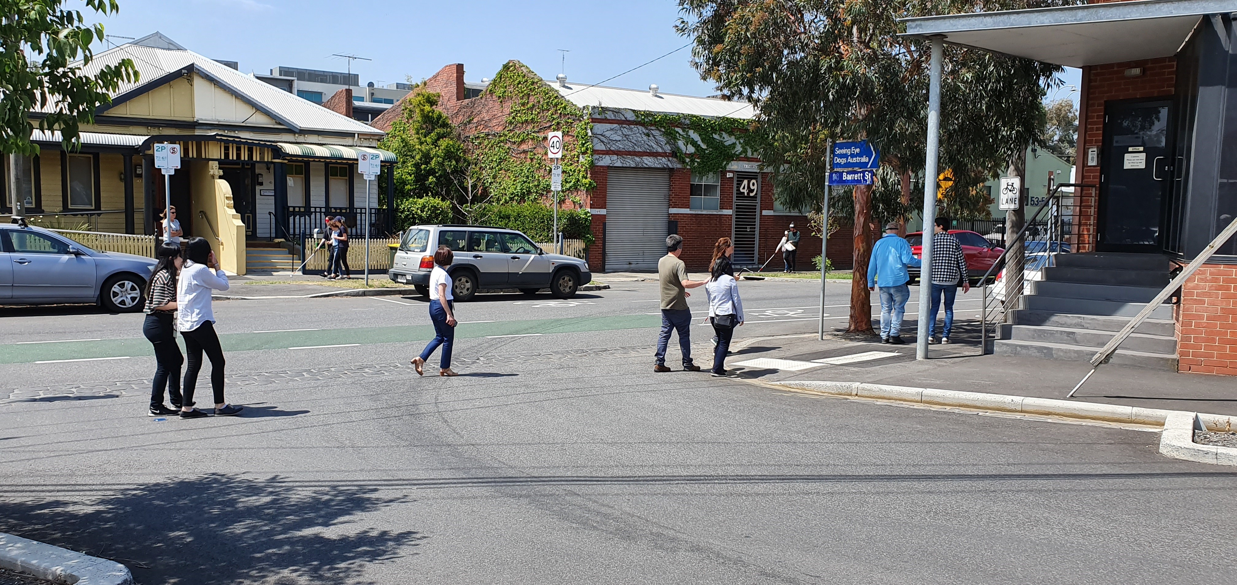 Blindfolded and guided Metro Staff members cross a road in Kensington, looking for the replacement bus stop.